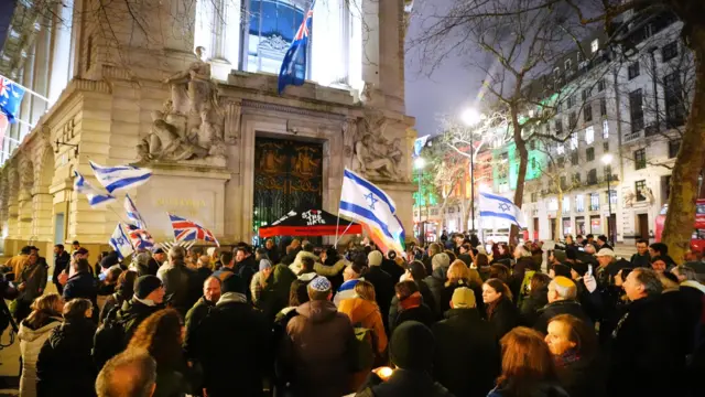 Crowds holding Israeli flags and Union Jacks stand outside the Australia High Commission in London