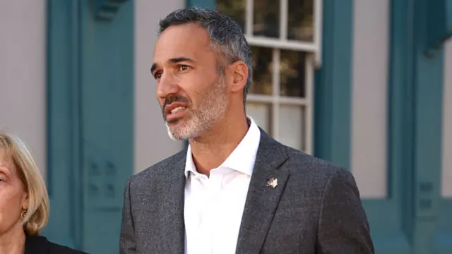 A man, wearing a suit, stands while speaking to press - file image
