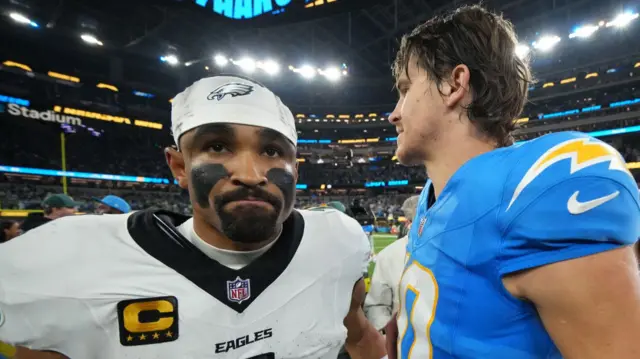 Philadelphia Eagles quarterback Jalen Hurts looking disappointed with Los Angeles Chargers quarterback Justin Herbert after losing at SoFi Stadium