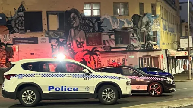 Vários carros de polícia estacionados no meio da rua com um prédio ao fundo