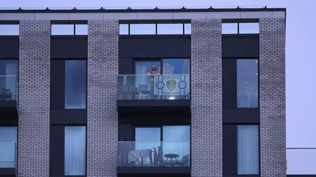 A Leeds fan displays a flag in an apartment overlooking the stadium prior to the Premier League match between Brentford and Leeds United at Gtech Community Stadium