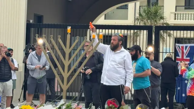 A man lights candles on a large menorah