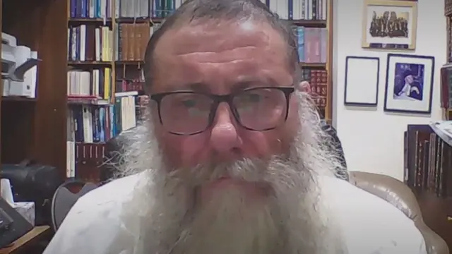 Rabbi Moshe Gutnick speaking to BBC News over a video call. With a long grey beard and wearing a shite shirt, he is sitting in front of several full bookcases