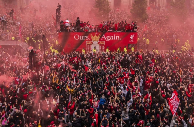Huge crowds of Liverpool fans greet the team bus as they let off red flares and wave flags