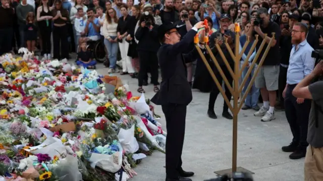 Rabbi Levi Wolff lights a menorah at Bondi Pavilion earlier today