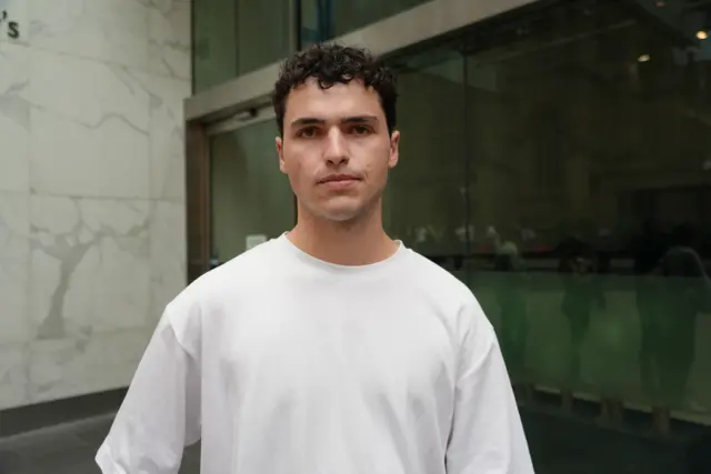 A young man with curly hair in a white t-hirt