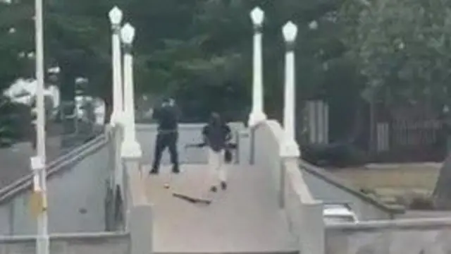 One man wearing all black is seen in the video shooting from a bridge by Bondi beach