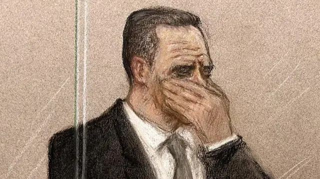 Court sketch of Paul Doyle in the dock at Liverpool Crown Court. He has his head in his hand and appears to be weeping. He is wearing a black suit and tie with a white shirt