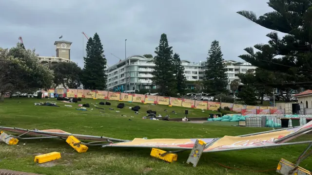 Abandoned belongings on a stretch of grass, with collapsed barriers surrounding the area.