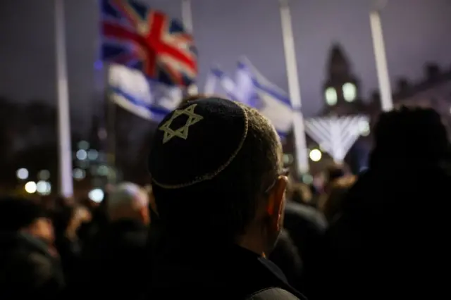 A man wearing a yarmulke looks out at a crowd in central London at night time