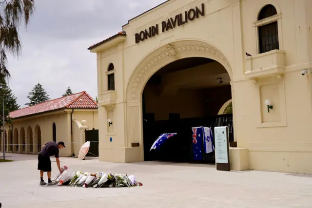 A man lays flowers in front of the Bondi pavilion