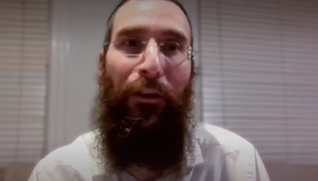 Rabbi Zalman Lewis speaking over a online video to call in his living room