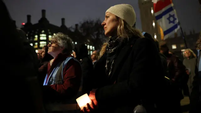 A woman with a white hat on stands in a crowd at night time in central London