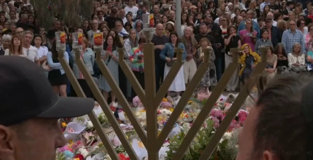 A crowd of people fill the scene at a memorial