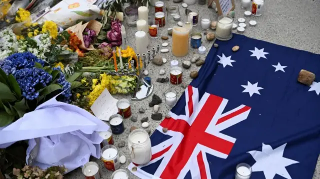 A view overhead of tributes laid on the ground including an Australian flag
