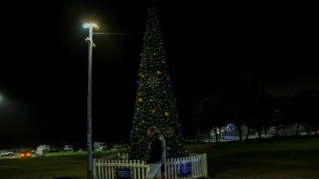 A pair walks past a Christmas tree on Bondi Beach on the evening of 14 December, the lights on which have been turned off