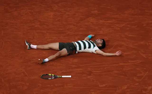 Carlos Alcaraz lies on the ground after the French Open final