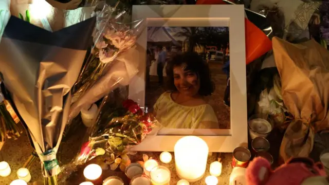 A photograph of Matilda can be seen among candles and flowers. Around a dozen candles have been lit in front of the framed photo of Matilda, who is smiling and wearing face paint