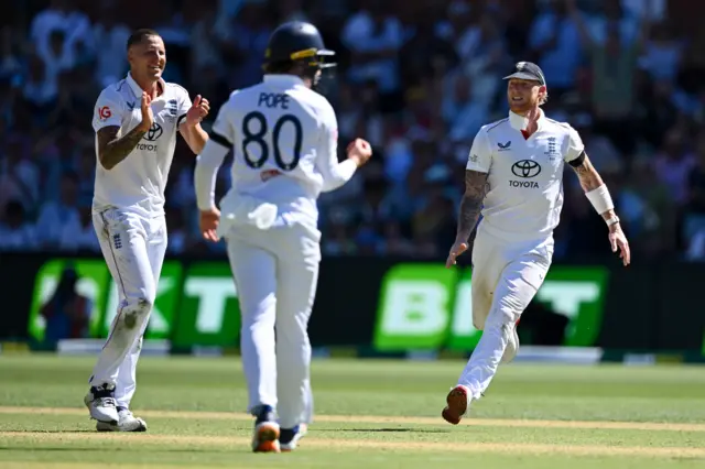 Brydon Carse and England celebrate the wicket of Pat Cummins