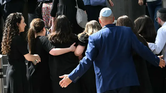 People arrive for the funeral of rabbi Eli Schlanger, dressed in black.