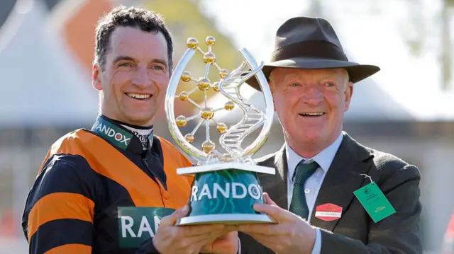 Jockey Patrick Mullins with his father the trainer Willie Mullins and the trophy after their horse Nick Rockett wins the Grand National