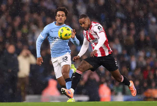 Rico Henry of Brentford controls the ball under pressure from Oscar Bobb of Manchester City