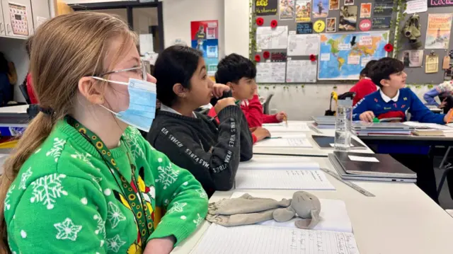 Children in a school classroom in Leeds with one girl wearing a facemask
