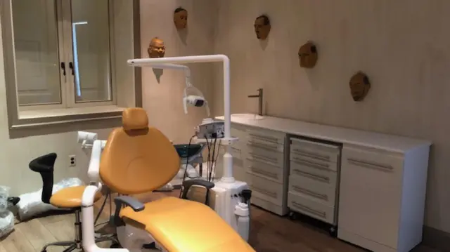 room with a dentist's chair and masks of men's faces on the walls