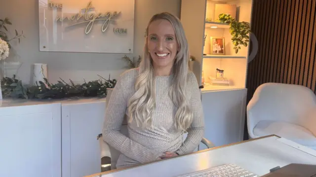 Woman sat at desk with hands on her lap