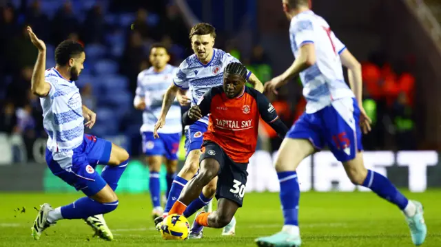 Luton's Gideon Kodua tries to dribble past several Reading players