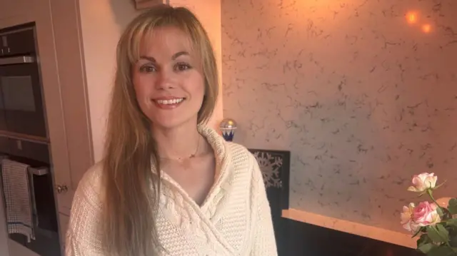Woman standing in her kitchen smiling