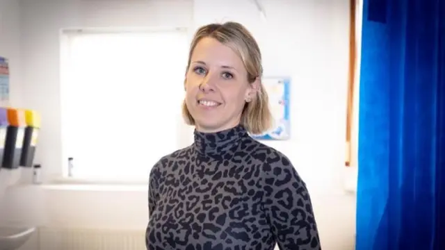 Woman in doctor's room smiling for camera