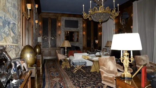 an ornate parlor room with golden fixtures, a chandelier, and tapestries on the walls