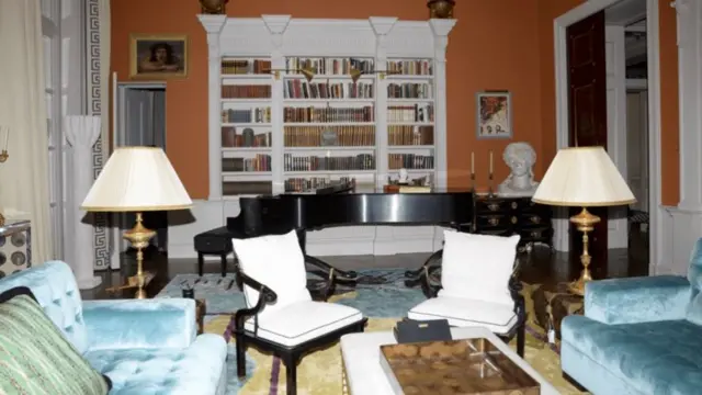 an ornate living room with a bookshelf, couches and chairs