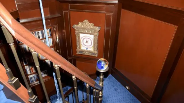 a curved wooden staircase lined with a blue rug