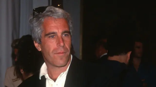 Jeffrey Epstein in white polo and black blazer with sunglasses on top of his head