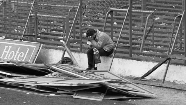 A Liverpool fan sits on the steps at Hillsborough surrounded by debris