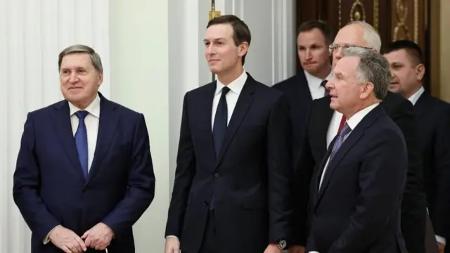 Six men stand in a group in suits