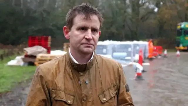 MP Mike Martin in a brown coat at a water station.