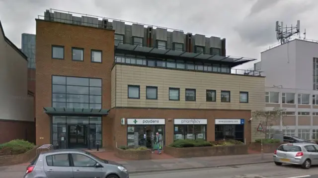 A brown and cream building with a pharmacy on the ground floor.