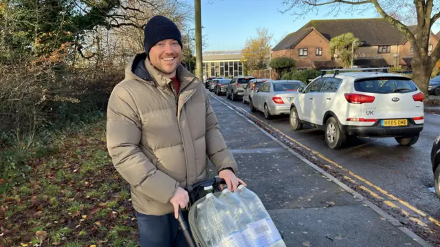 Young man with pushchair in street wearing hat