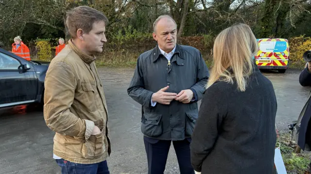 Sir Ed Davey and Mike Martin speak to a woman with blonde hair.