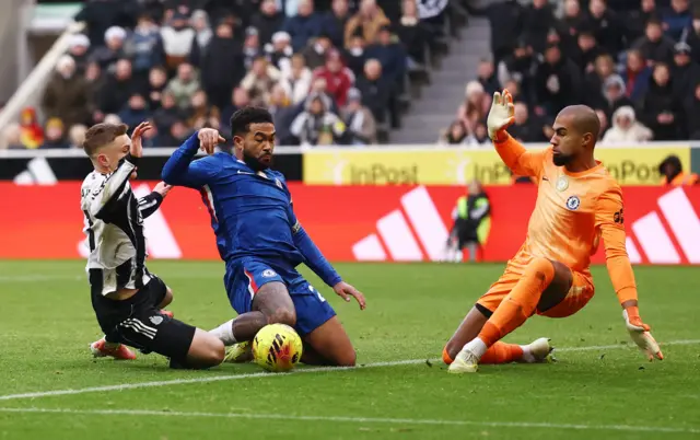 Chelsea's Robert Sanchez and Chelsea's Reece James in action with Newcastle United's Harvey Barnes during Premier League fixture.