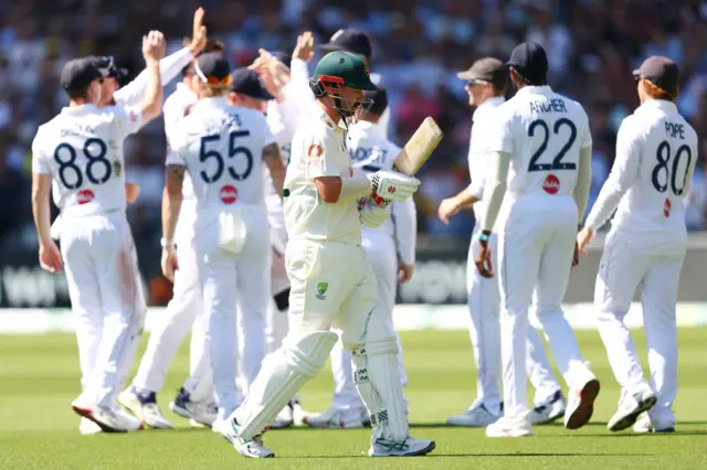 Travis Head walks off after being dismissed as England celebrate in the background