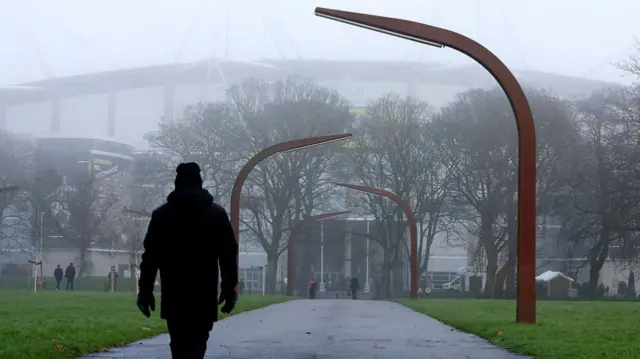 A fan walks towards a misty MKM Stadium