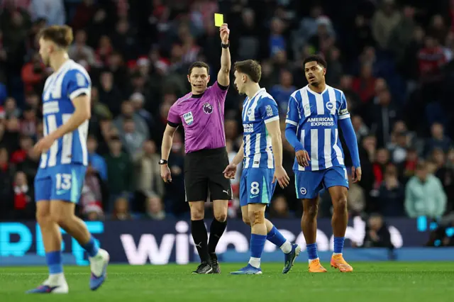 Brajan Gruda of Brighton & Hove Albion is shown a yellow card by referee Darren England
