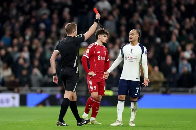 : Xavi Simons of Tottenham Hotspur is shown a red card
