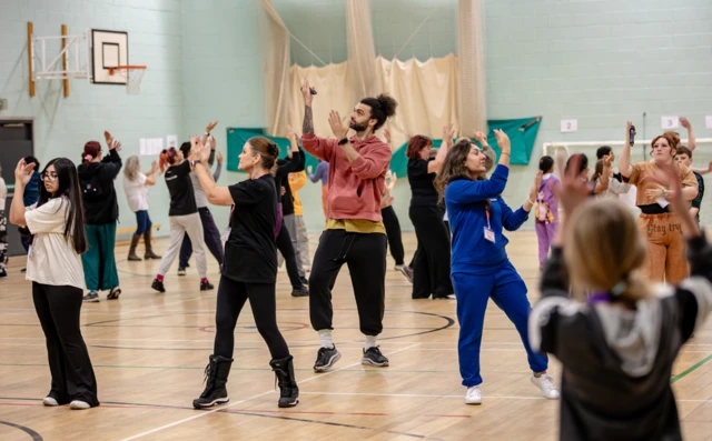 Dancers rehearse in a sports hall