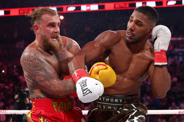 Anthony Joshua and Jake Paul's arms are tangled as they box