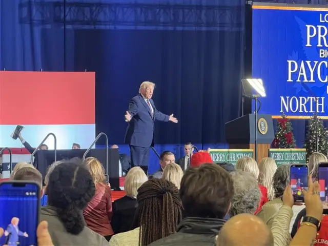 Donald Trump, arms outstretched, on a stage in front of a blue backdrop